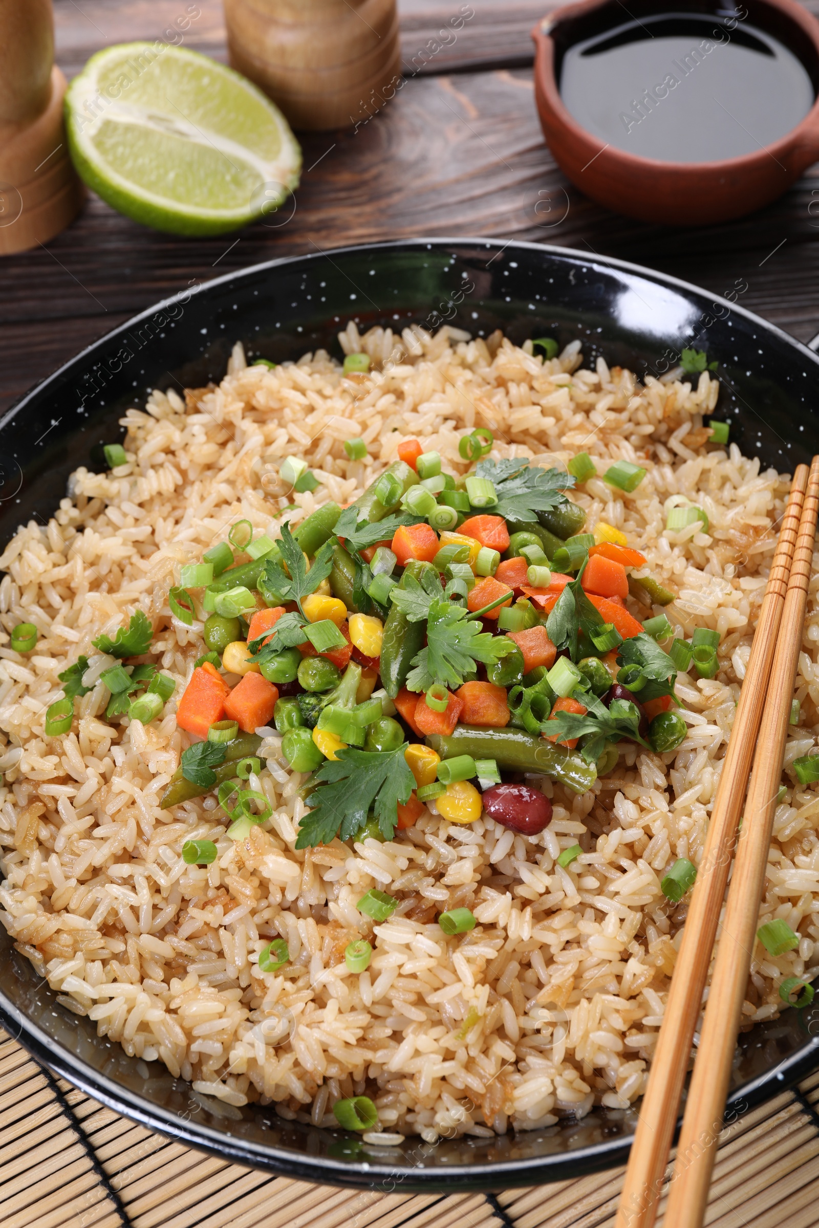 Photo of Tasty fried rice with vegetables served on wooden table, closeup