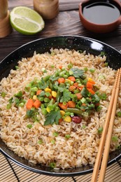 Photo of Tasty fried rice with vegetables served on wooden table, closeup