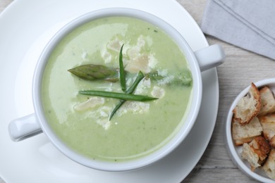 Photo of Delicious asparagus soup with green onion served on white wooden table, flat lay