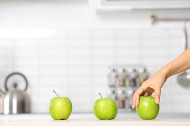 Photo of Woman taking ripe green apple from kitchen counter, closeup. Space for text