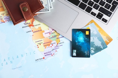 Photo of Flat lay composition with credit cards, money and laptop on map. Travel agency