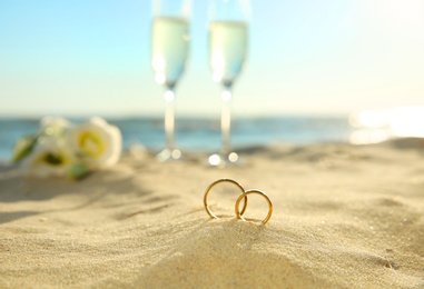 Photo of Beautiful gold wedding rings on sandy beach