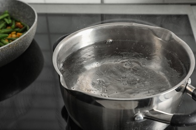 Pot with boiling water on electric stove, closeup