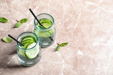 Photo of Jars with fresh cucumber water on grey background. Space for text