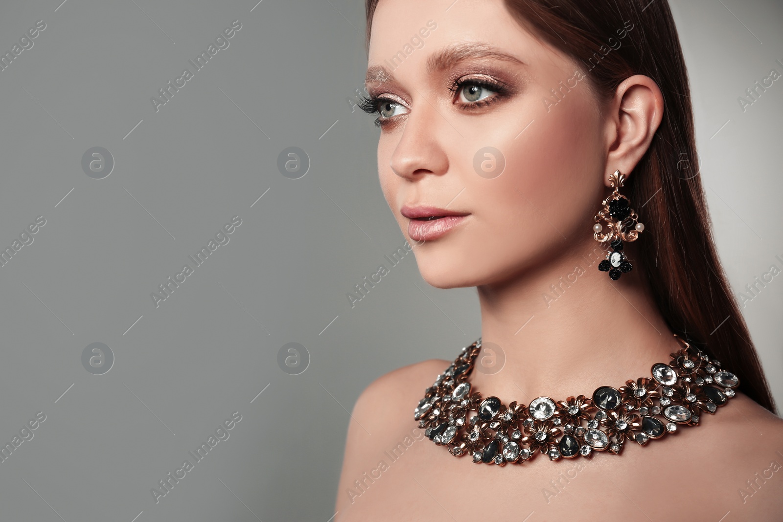 Photo of Beautiful woman with stylish jewelry on grey background, space for text