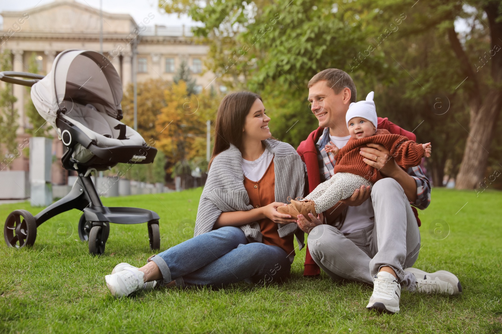 Photo of Happy parents with their adorable baby on green grass in park