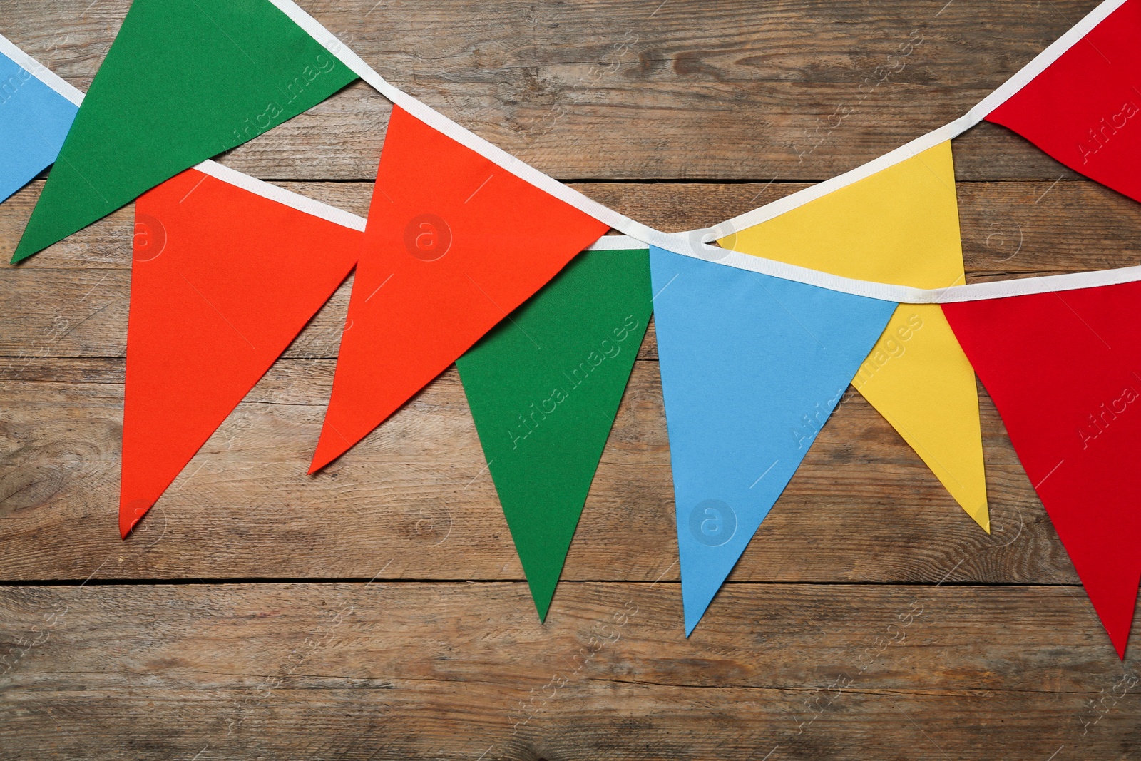 Photo of Buntings with colorful triangular flags on wooden background