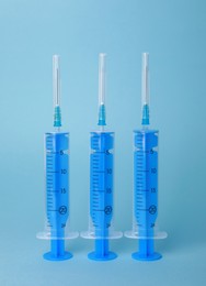 Photo of Disposable syringes with needles on light blue background