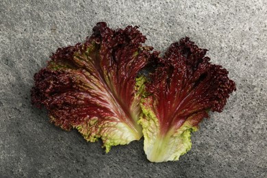 Photo of Leaves of fresh red coral lettuce on grey table, top view