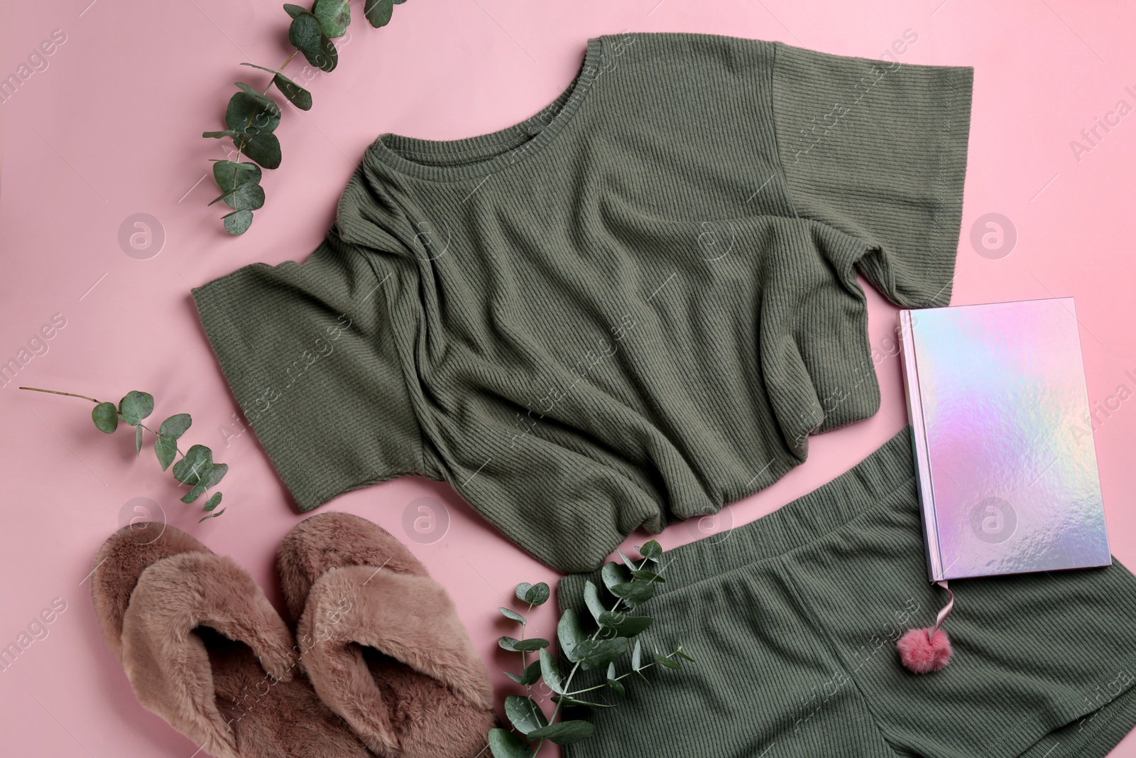 Photo of Fluffy slippers, pajamas and notebook on pink background, flat lay. Comfortable home outfit