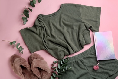 Fluffy slippers, pajamas and notebook on pink background, flat lay. Comfortable home outfit