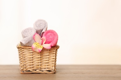 Clean towels with flower in basket on table. Space for text