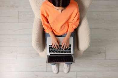 Woman working with laptop in armchair, top view