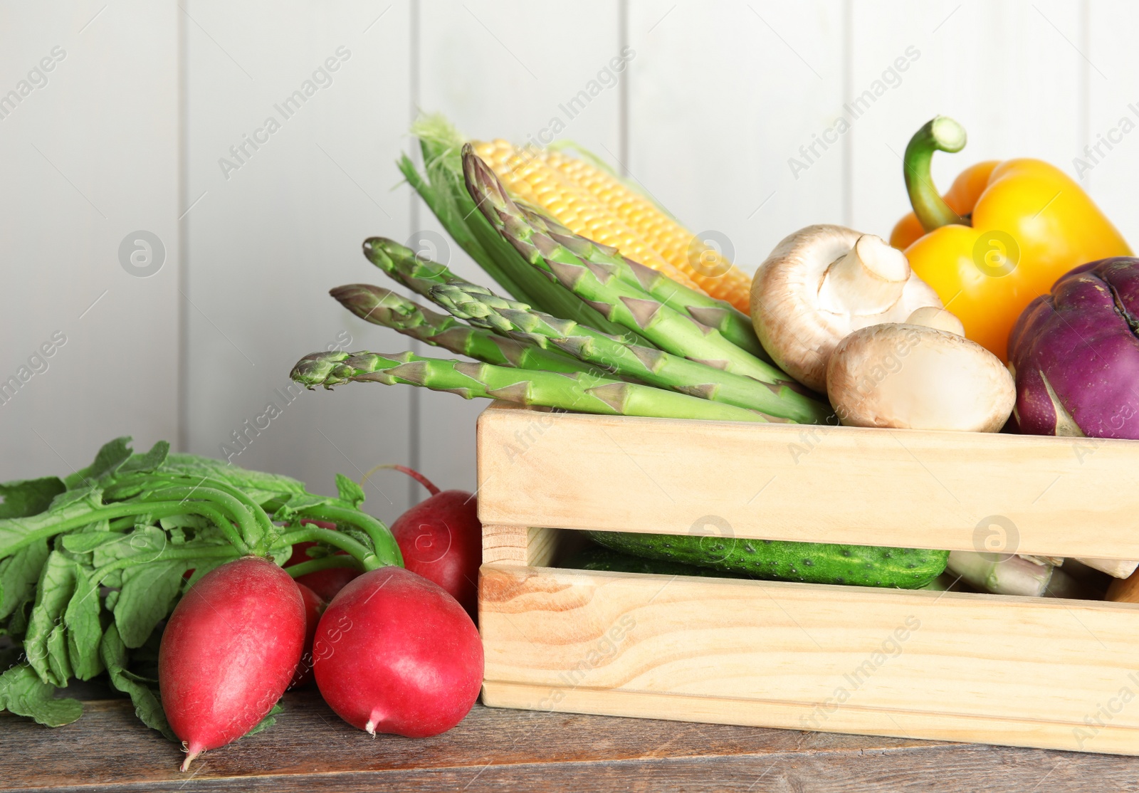 Photo of Crate with assortment of fresh vegetables on table against light background