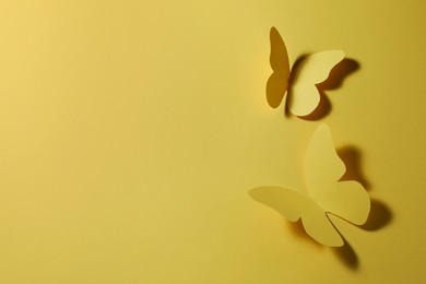 Photo of Paper butterflies on yellow background, top view. Space for text