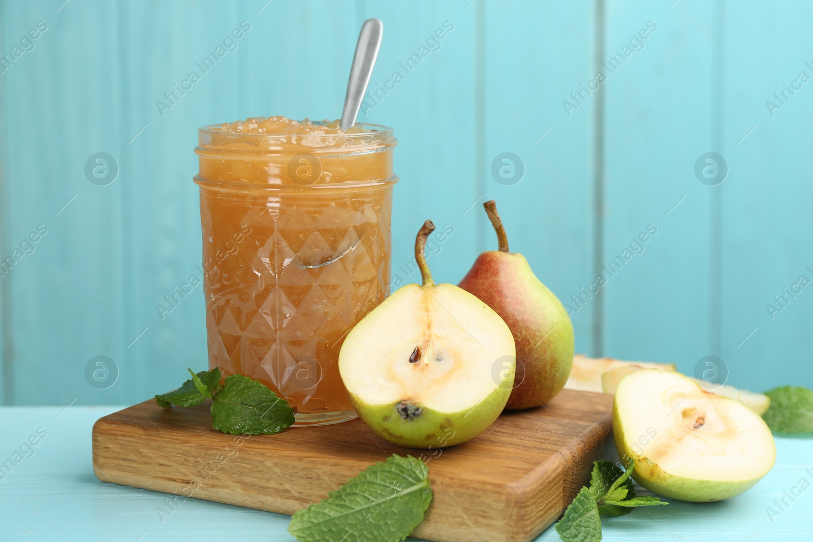 Photo of Tasty homemade pear jam and fresh fruits on light blue wooden table