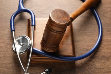 Photo of Law concept. Gavel and stethoscope on wooden table, closeup