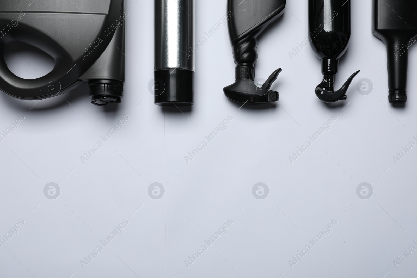 Photo of Black bottles and canister on white background, flat lay. Space for text