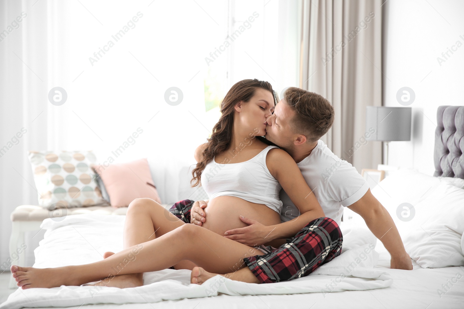 Photo of Pregnant woman with her husband in bedroom. Space for text
