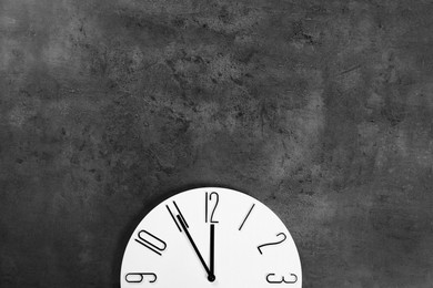 Photo of Stylish analog clock hanging on grey wall, space for text. New Year countdown