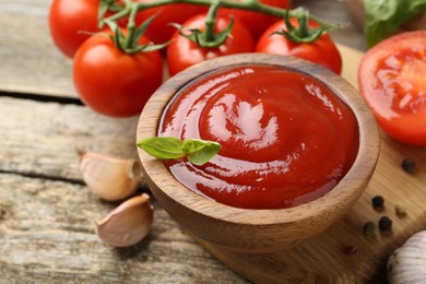 Photo of Tasty ketchup, fresh tomatoes, basil and spices on wooden table