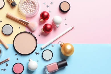 Flat lay composition with makeup products and Christmas decor on color background. Space for text