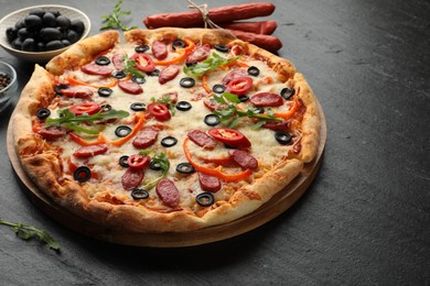 Photo of Tasty pizza and ingredients on black table