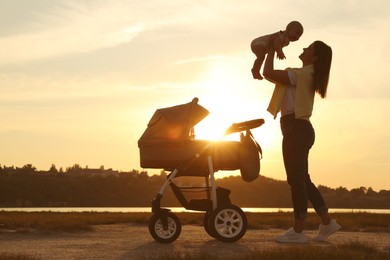 Photo of Happy mother with baby near river at sunset