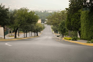 Photo of Beautiful city street with wide asphalt road and green trees