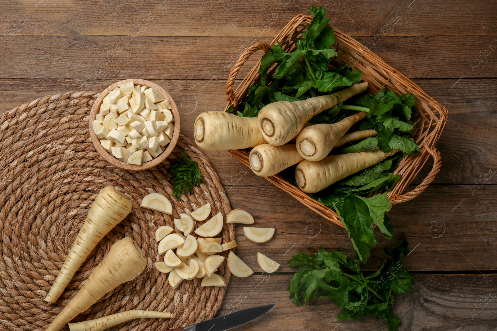 Photo of Whole and cut parsnips on wooden table, flat lay