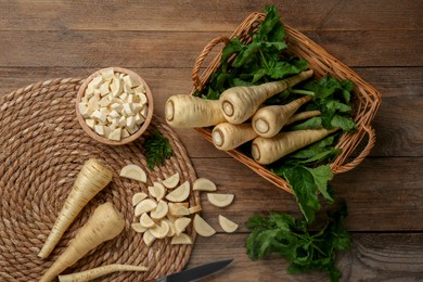 Photo of Whole and cut parsnips on wooden table, flat lay