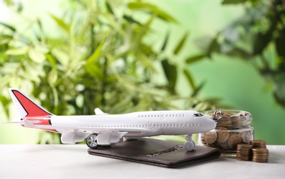 Photo of Plane model, passport and coins on table against blurred background. Space for text