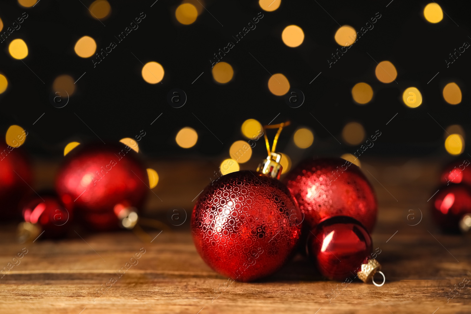 Photo of Beautiful Christmas balls on wooden table against blurred festive lights. Space for text