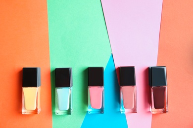 Photo of Bottles of nail polish on color background, top view with space for text