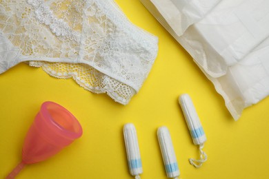 Flat lay composition with woman's panties and menstrual hygiene products on yellow background
