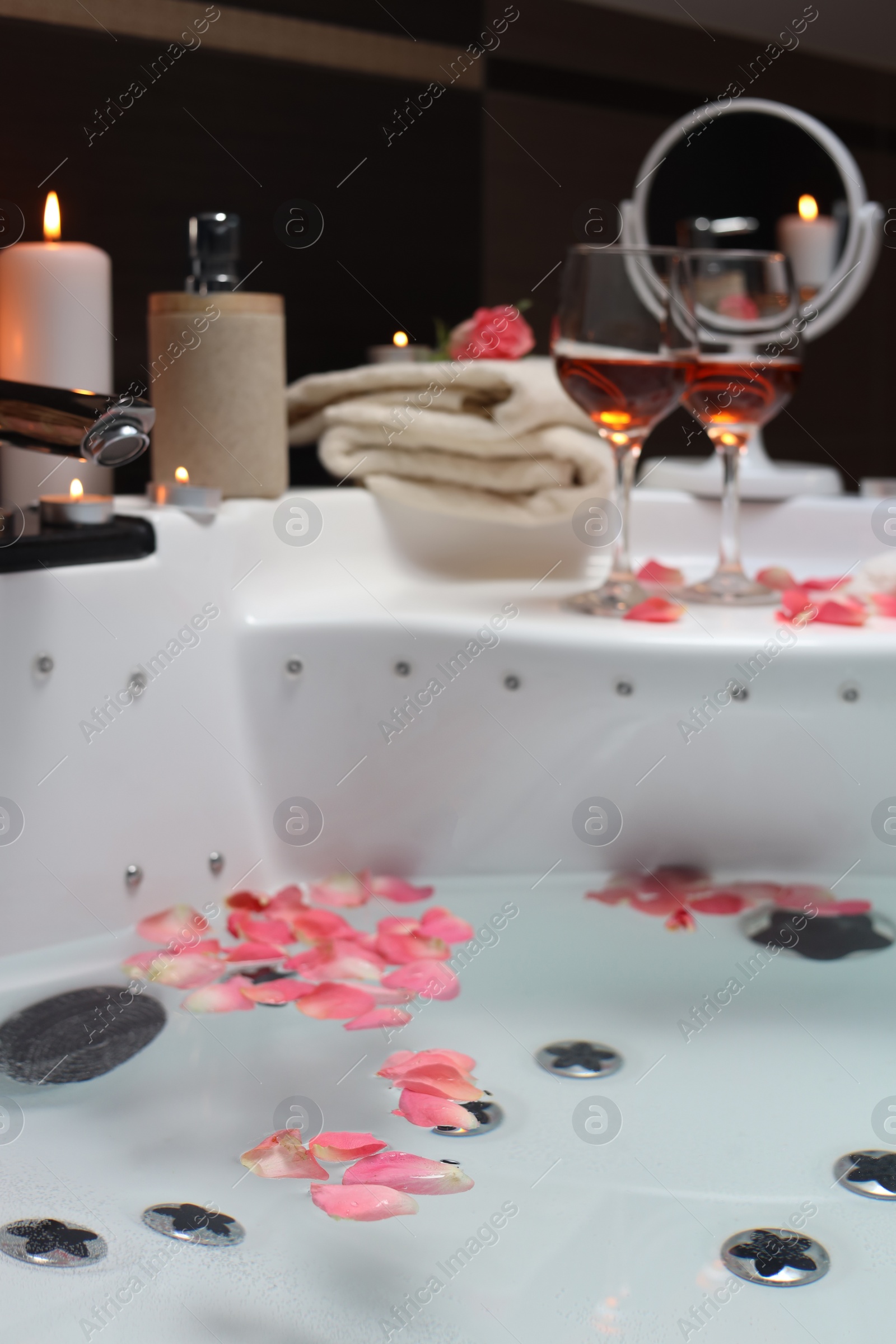 Photo of Bathtub with glasses of wine and candles indoors. Romantic atmosphere