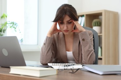 Photo of Overwhelmed office worker sitting at table with laptop indoors