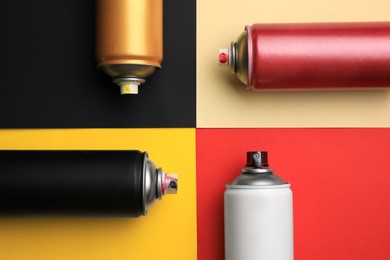 Cans of different graffiti spray paints on color background, flat lay