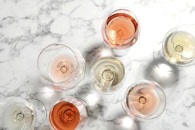 Different glasses with wine on marble background, flat lay