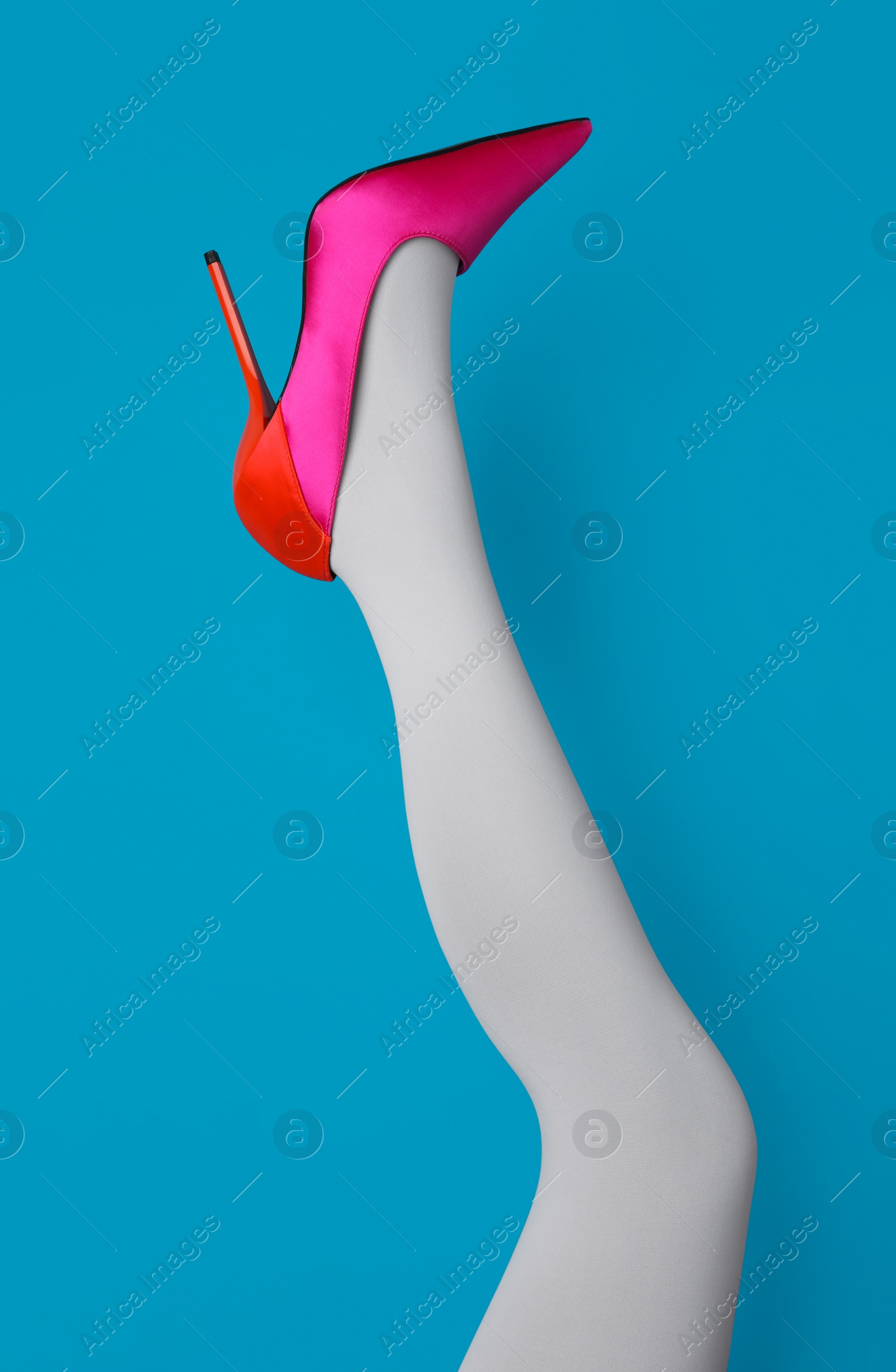 Photo of Woman wearing white tights and high heel shoe on light blue background, closeup