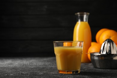 Photo of Tasty fresh oranges and juice on black table, closeup. Space for text