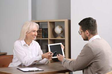 Photo of Boss pointing at tablet while discussing work issues with employee in office