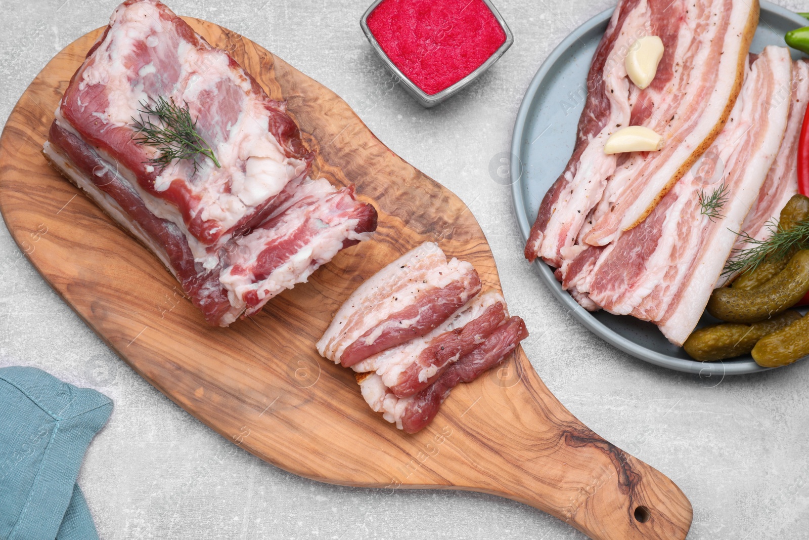 Photo of Tasty pork fatback with pickled cucumbers, garlic and dill on grey table, flat lay