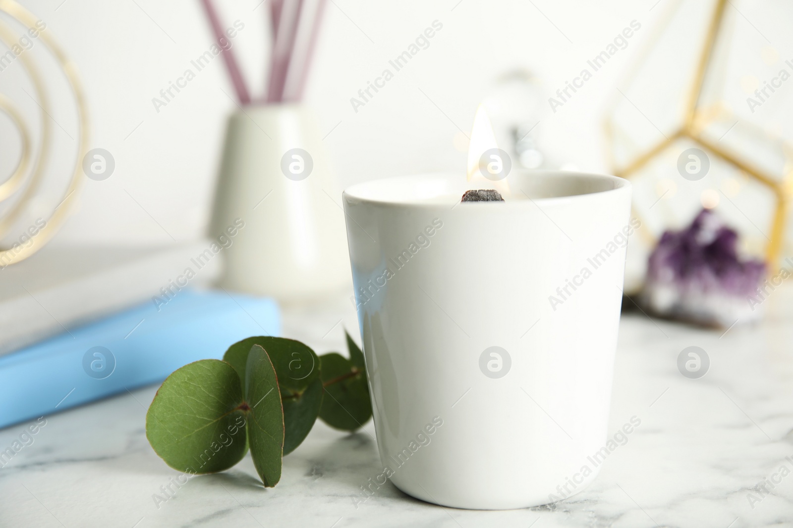 Photo of Burning candle with wooden wick on white marble table