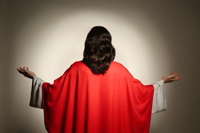 Jesus Christ with outstretched arms on beige background, back view