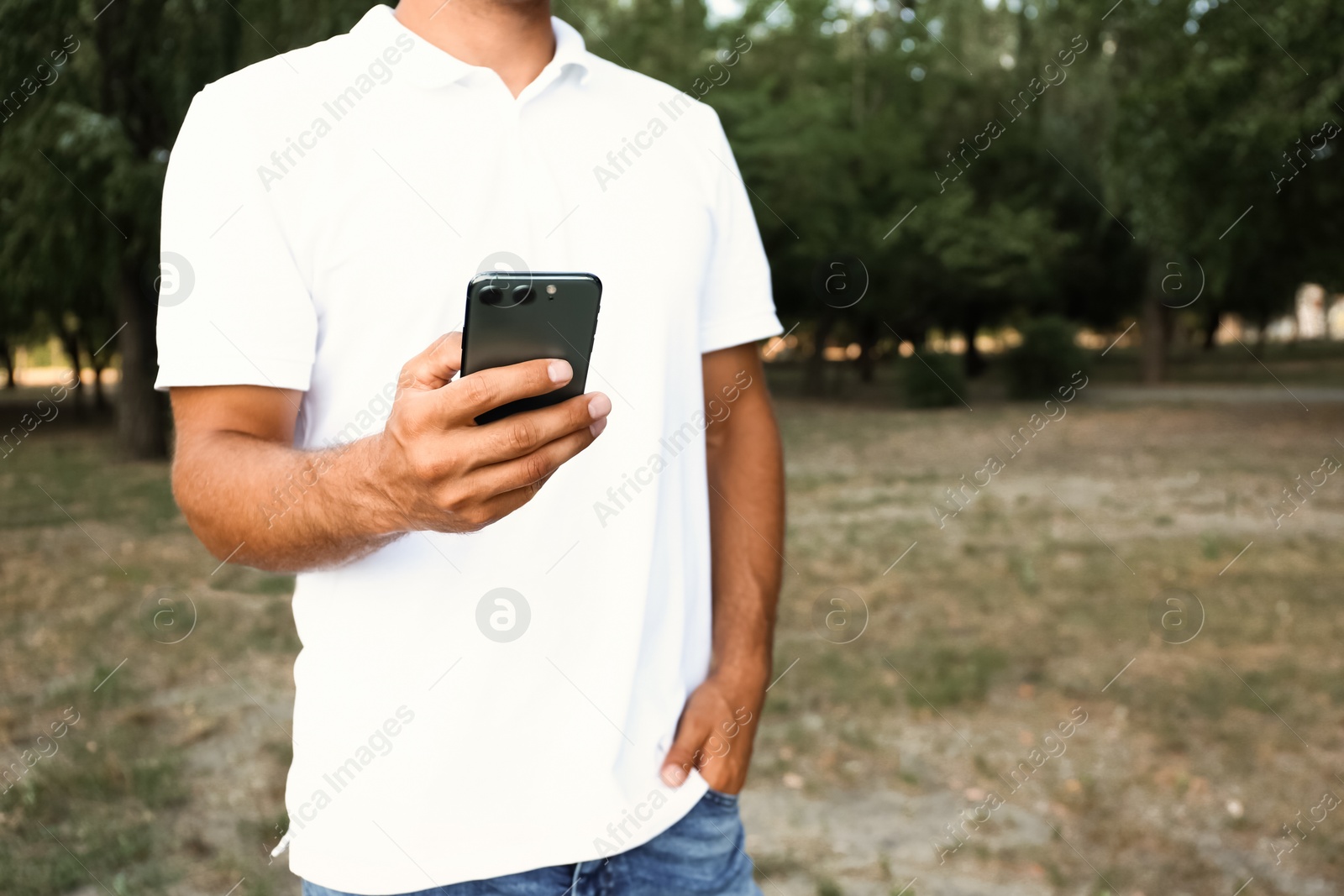 Photo of Man using modern mobile phone in park, closeup