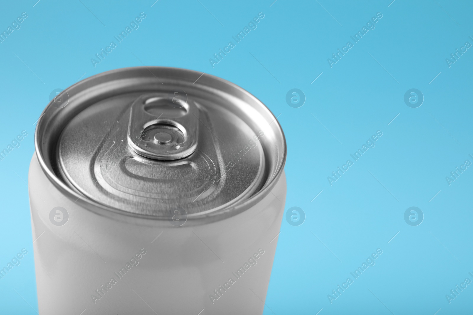 Photo of Can of energy drink on light blue background, closeup. Space for text