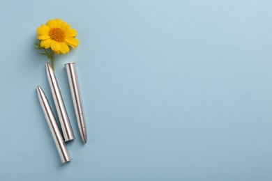 Bullets and beautiful flower on light blue background, flat lay. Space for text