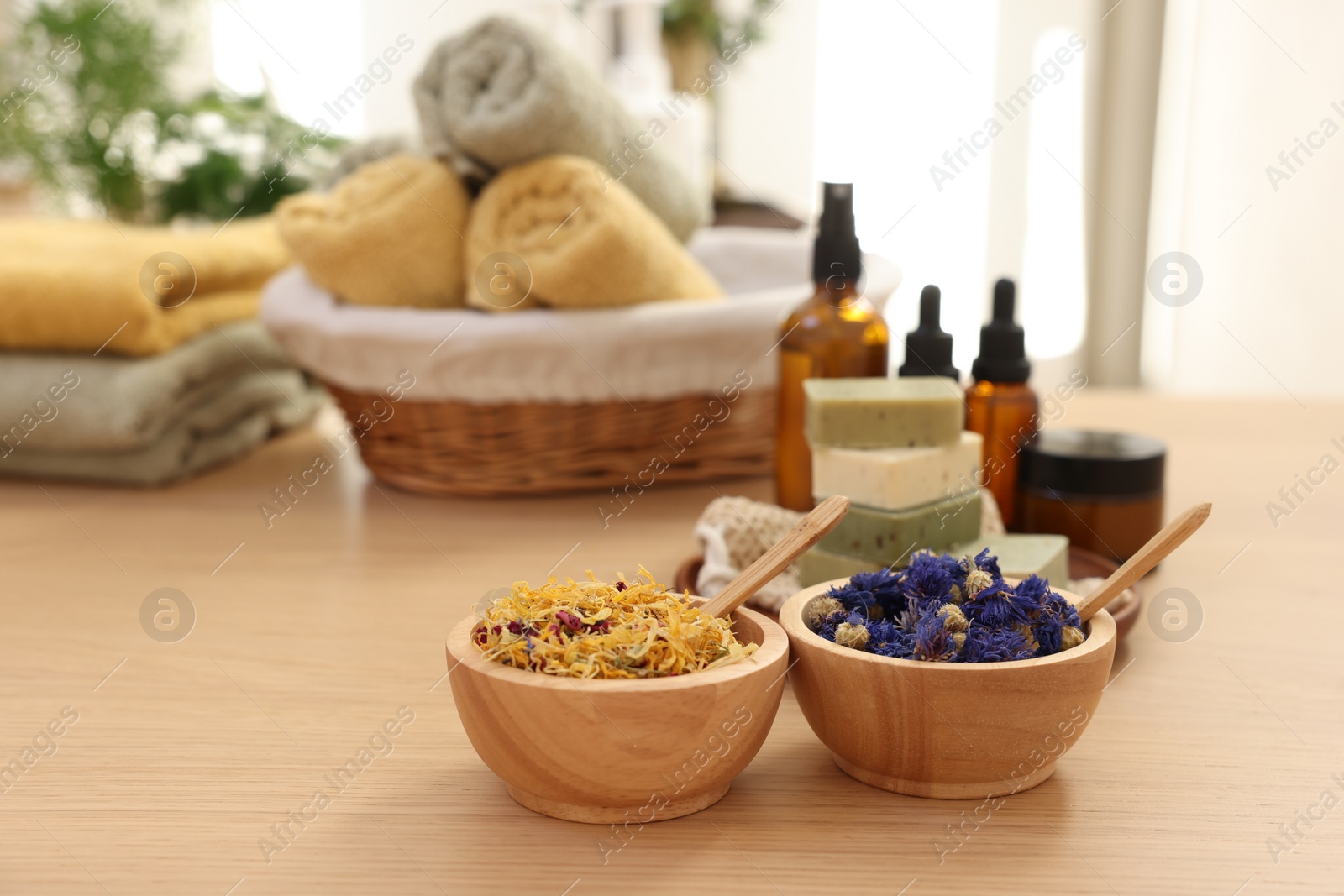 Photo of Bowls with dry flowers on wooden table indoors, space for text. Spa time