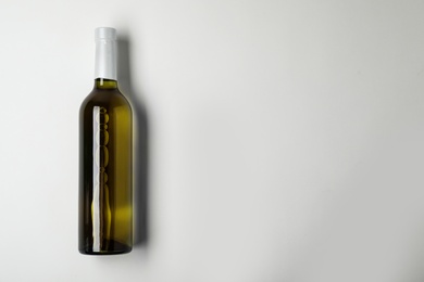 Bottle of expensive white wine on light background, top view